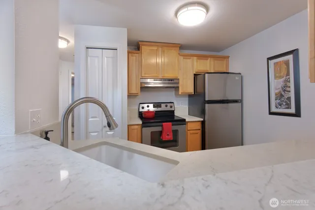 a kitchen with stainless steel appliances granite countertop a refrigerator and a stove top oven