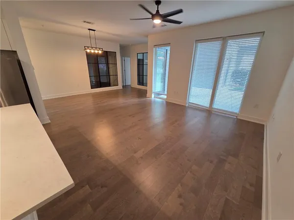 an empty room with wooden floor cabinet and windows