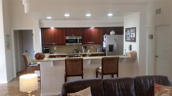 a kitchen with kitchen island stainless steel appliances a sink a stove a refrigerator cabinets and a dining table