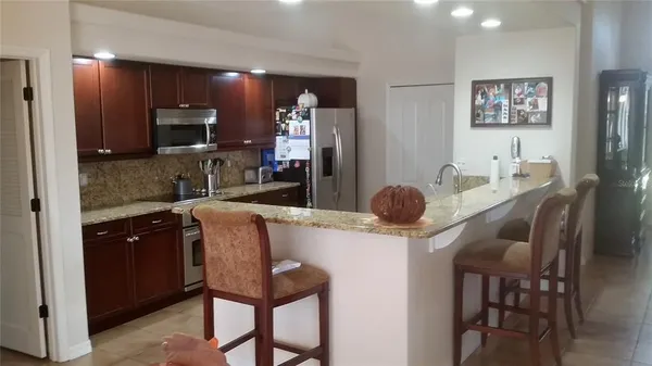 a kitchen with stainless steel appliances granite countertop a refrigerator a sink a stove a dining table and chairs