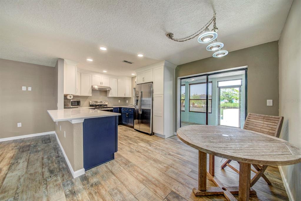 4266 Deleon Drive Hernando Beach, FL 34607 - Photo 11 of 65 a kitchen with a table chairs refrigerator and wooden floor