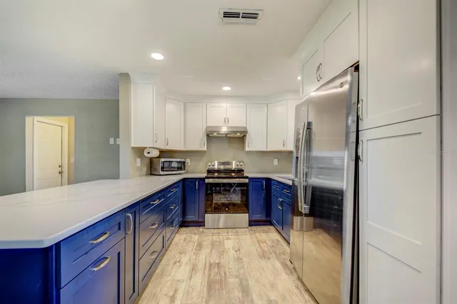 a kitchen with stainless steel appliances granite countertop a refrigerator a stove and a sink with wooden floor
