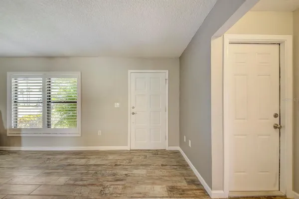 a view of an empty room with wooden floor and a window