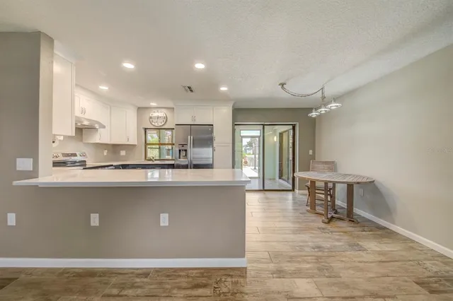 a living room with stainless steel appliances granite countertop wooden floor a large window and a counter top space