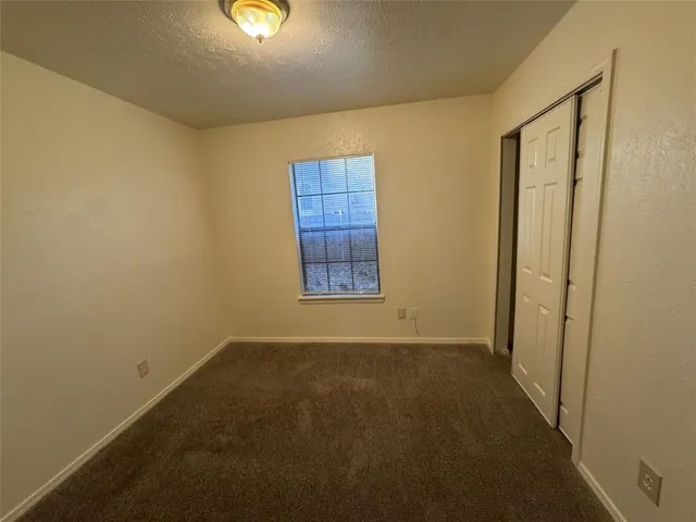 an empty room with chandelier fan and windows