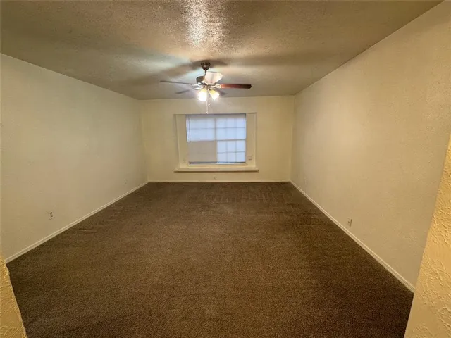 an empty room with a ceiling fan and a window