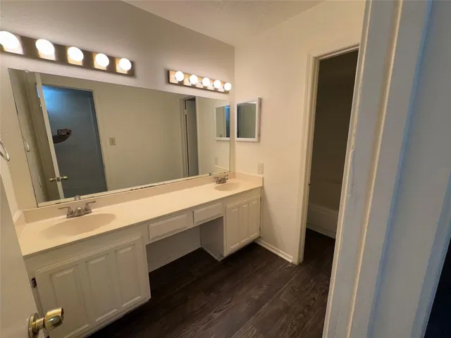 a bathroom with a granite countertop bathtub shower sink vanity and toilet
