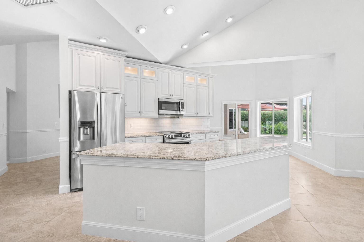 a kitchen with stainless steel appliances granite countertop a sink and a refrigerator