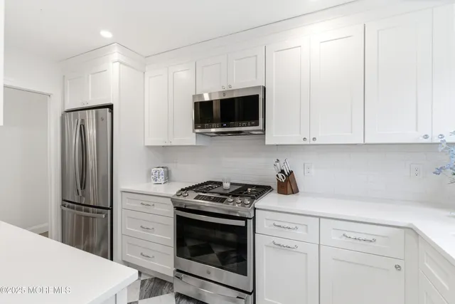 a kitchen with white cabinets and stainless steel appliances