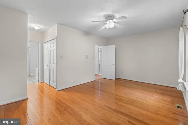 an empty room with wooden floor and fan