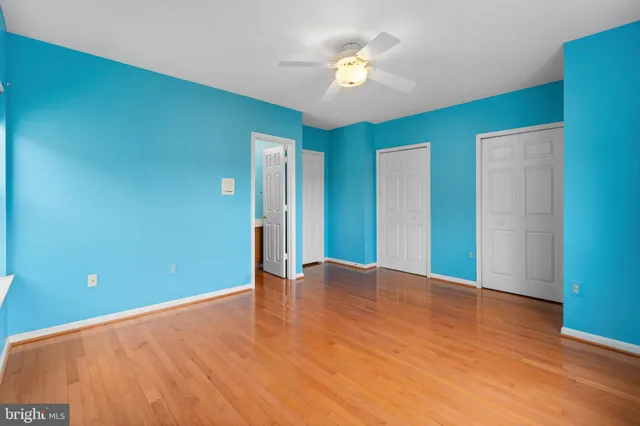 an empty room with wooden floor and chandelier fan