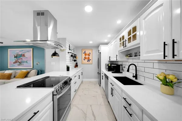 a kitchen with stainless steel appliances a sink a stove a refrigerator a counter top space and cabinets