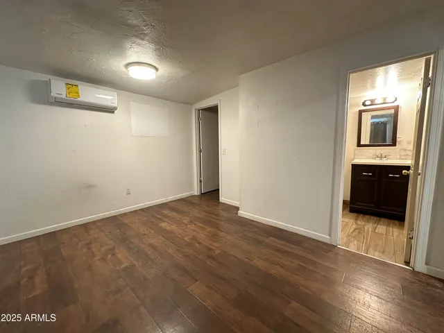 a view of a hallway with wooden floor and a kitchen