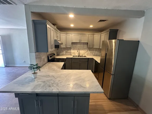 a kitchen with kitchen island a sink a stove a refrigerator and cabinets