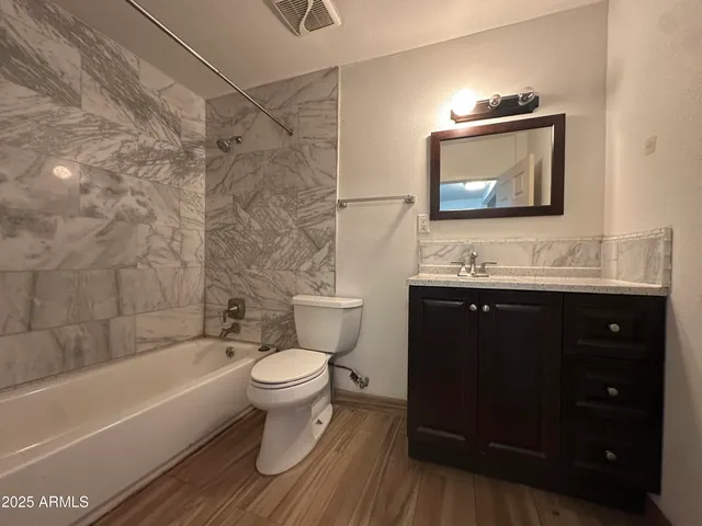 a bathroom with a toilet a sink a mirror a bathtub and shower