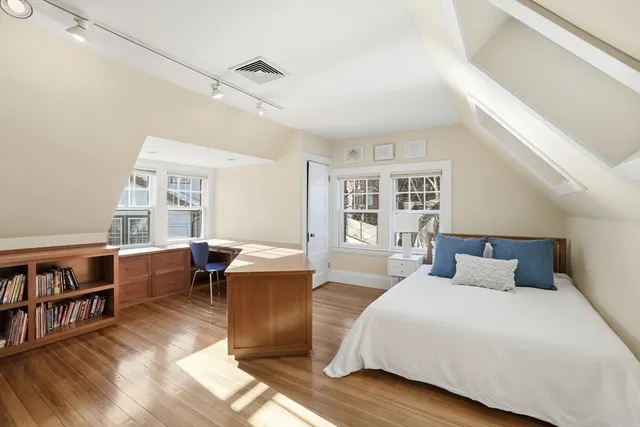 a bedroom with a bed and a bookshelf with wooden floor