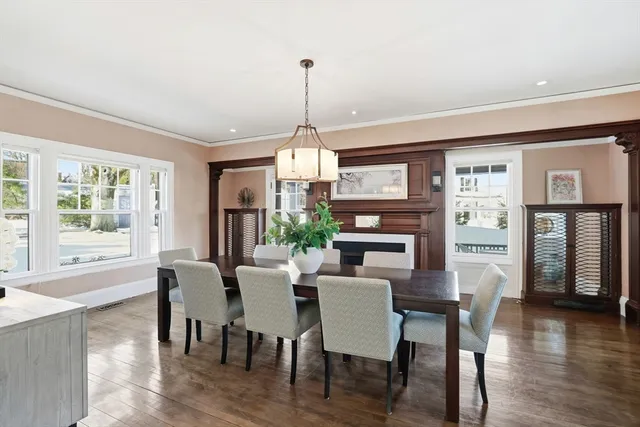 a dining room with wooden floor a chandelier a wooden table and chairs