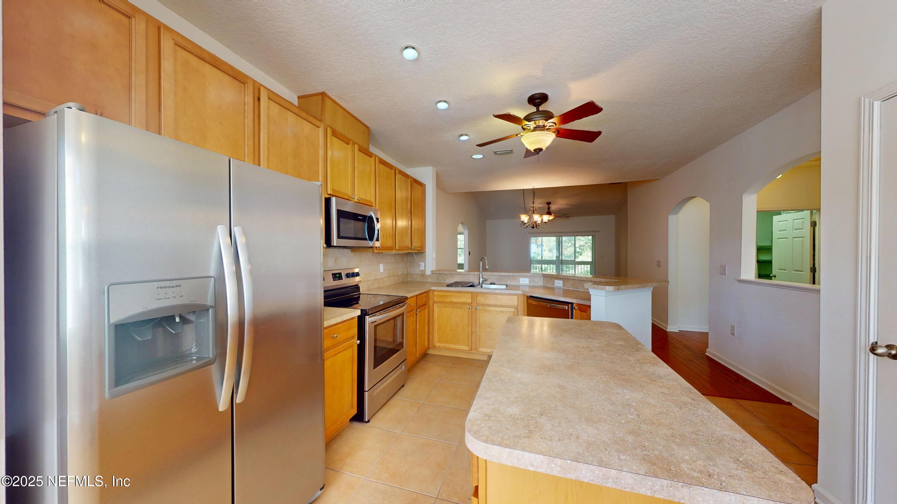 5663 Greenland Road, Unit 1004 Jacksonville, FL 32258 - Photo 8 of 35 a kitchen with stainless steel appliances granite countertop a refrigerator a oven a sink with dining table and chairs