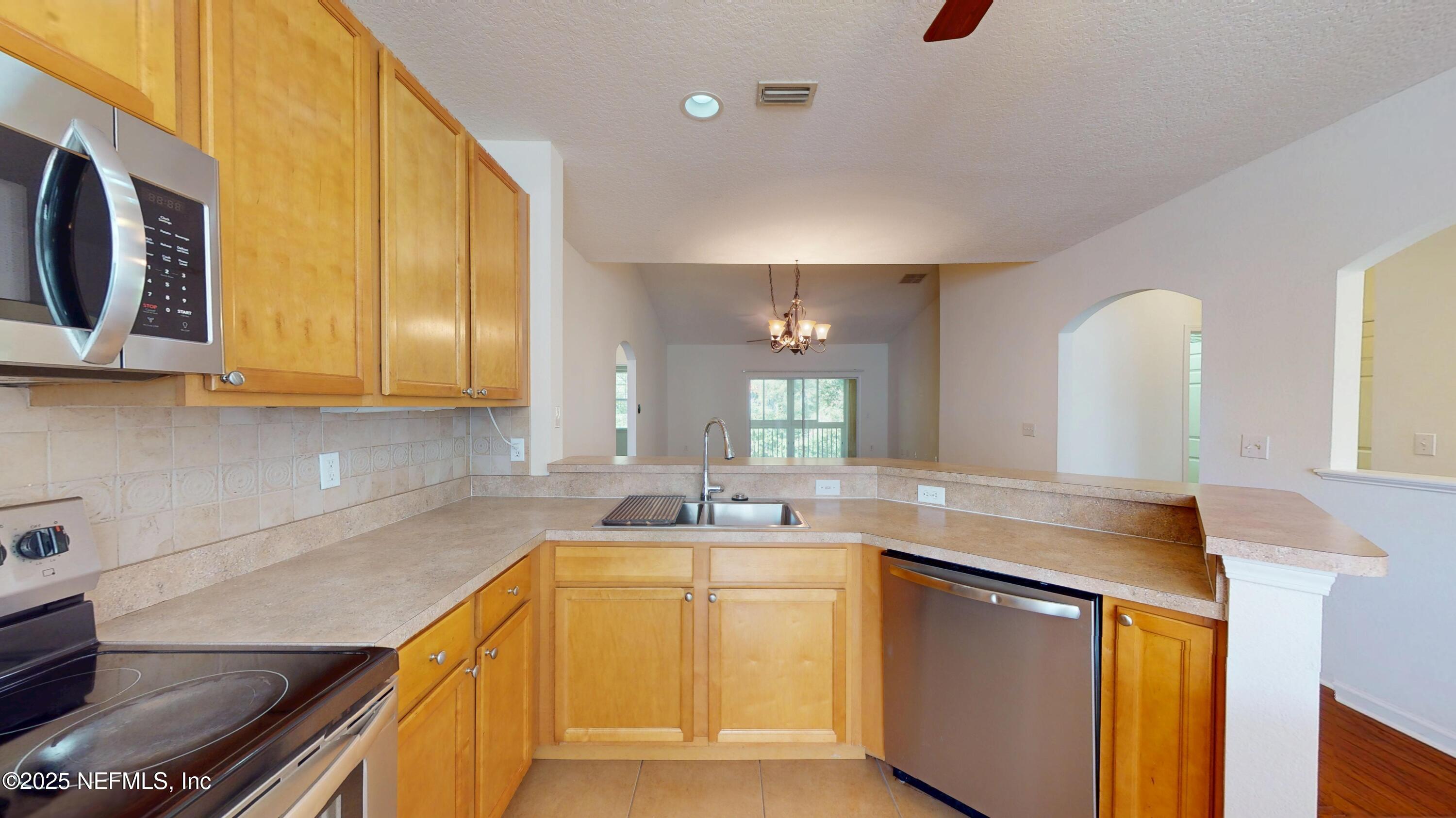 5663 Greenland Road, Unit 1004 Jacksonville, FL 32258 - Photo 9 of 35 a kitchen with stainless steel appliances granite countertop a sink a microwave cabinets and a stove top oven