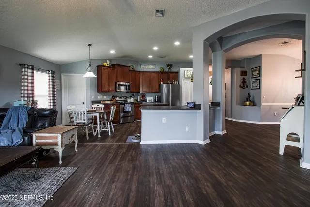 a living room with lots of wooden furniture and kitchen view