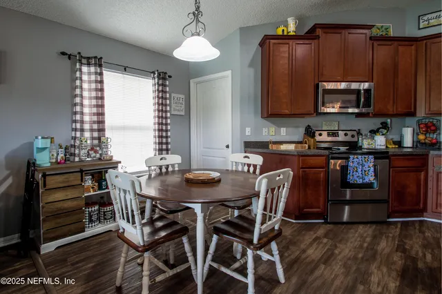 a kitchen with stainless steel appliances granite countertop a stove top oven a sink a dining table and chairs with wooden floor