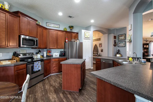 a kitchen with stainless steel appliances granite countertop a stove a sink dishwasher a refrigerator and a microwave
