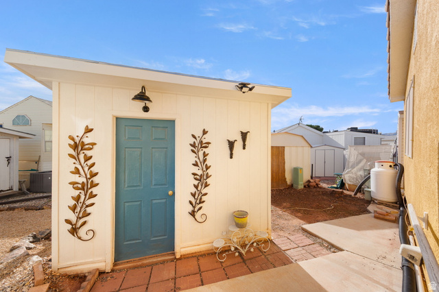 1225 North Dixie Downs Road, Unit 161 St. George, UT 84770 - Photo 17 of 21 Detached accessory structure featuring a blue paneled door, exterior wall sconce, and decorative wall accents