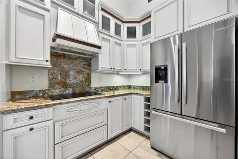 a kitchen with kitchen island granite countertop stainless steel appliances a sink a counter top cabinets and a chandelier