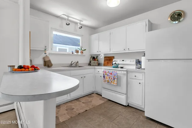 a kitchen with stainless steel appliances a sink a stove a refrigerator a white table and cabinets