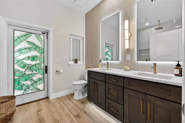 a bathroom with a double vanity sink toilet and a mirror