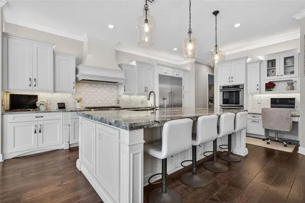a large kitchen with cabinets chairs and wooden floor