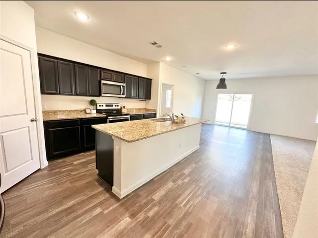 a large kitchen with stainless steel appliances kitchen island granite countertop a refrigerator and a stove top oven