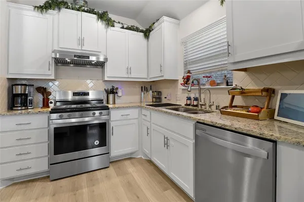 a kitchen with stainless steel appliances granite countertop a stove a sink and a microwave