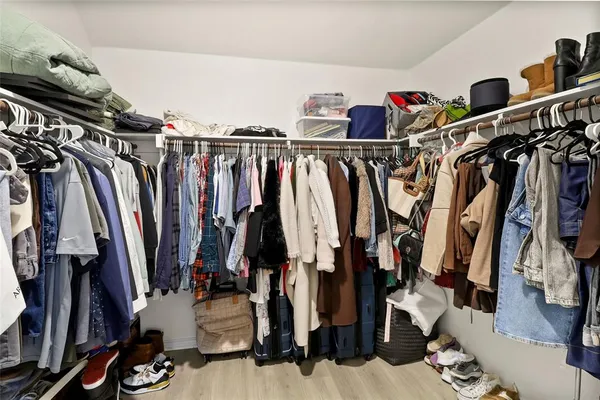 a view of walk in closet with clothes and shoes