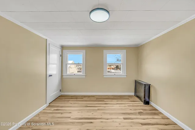a view of an empty room with window and wooden floor