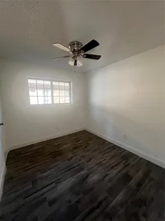 an empty room with wooden floor a ceiling fan and windows