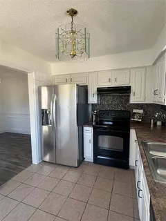 a kitchen with granite countertop a refrigerator and a stove top oven