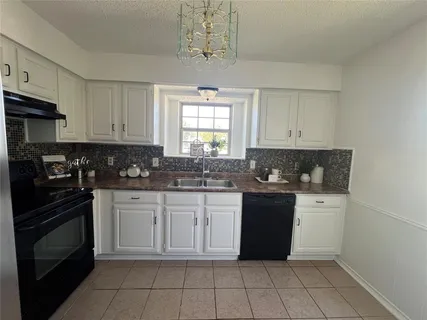 a white kitchen with a stove top oven and cabinets