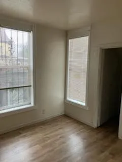 an empty room with wooden floor and windows
