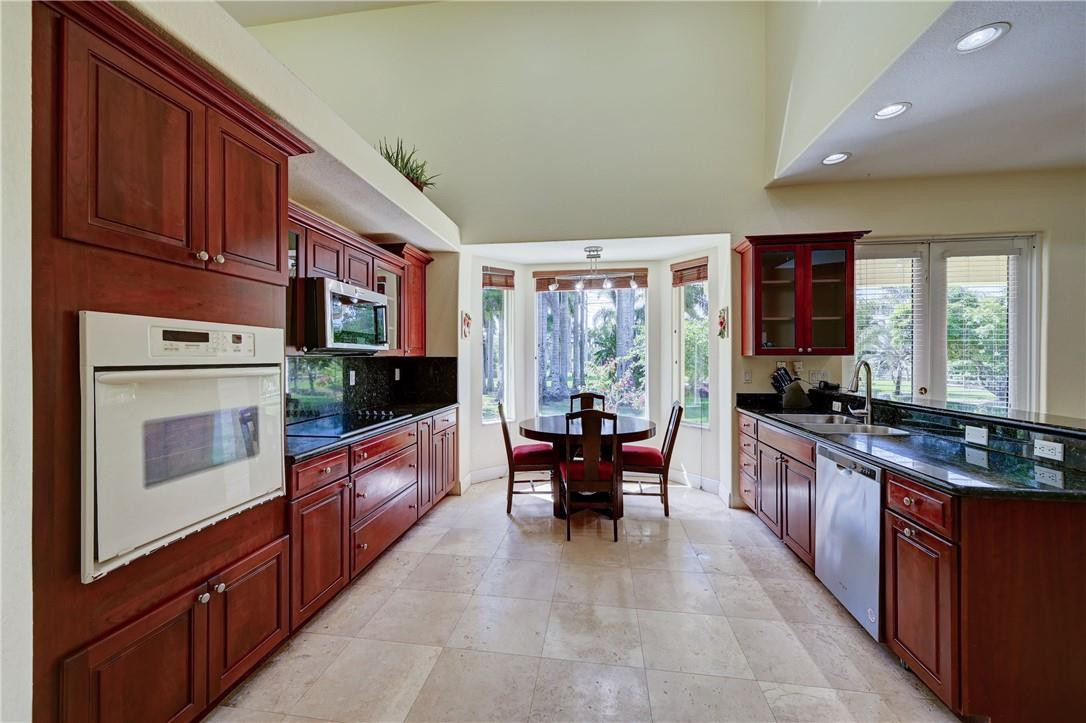 17400 Southwest 66th Street Southwest Ranches, FL 33331 - Photo 13 of 38 a large kitchen with stainless steel appliances granite countertop a stove top oven a sink dishwasher a dining table and chairs with wooden floor