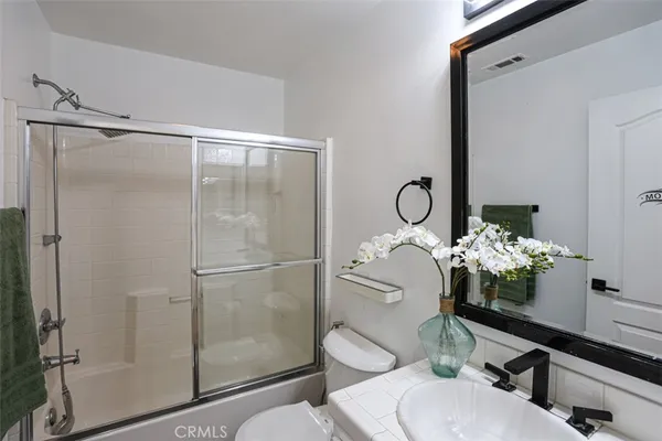 a bathroom with a shower sink mirror and toilet