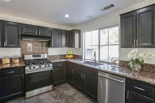 a kitchen with granite countertop stainless steel appliances a sink stove and cabinets