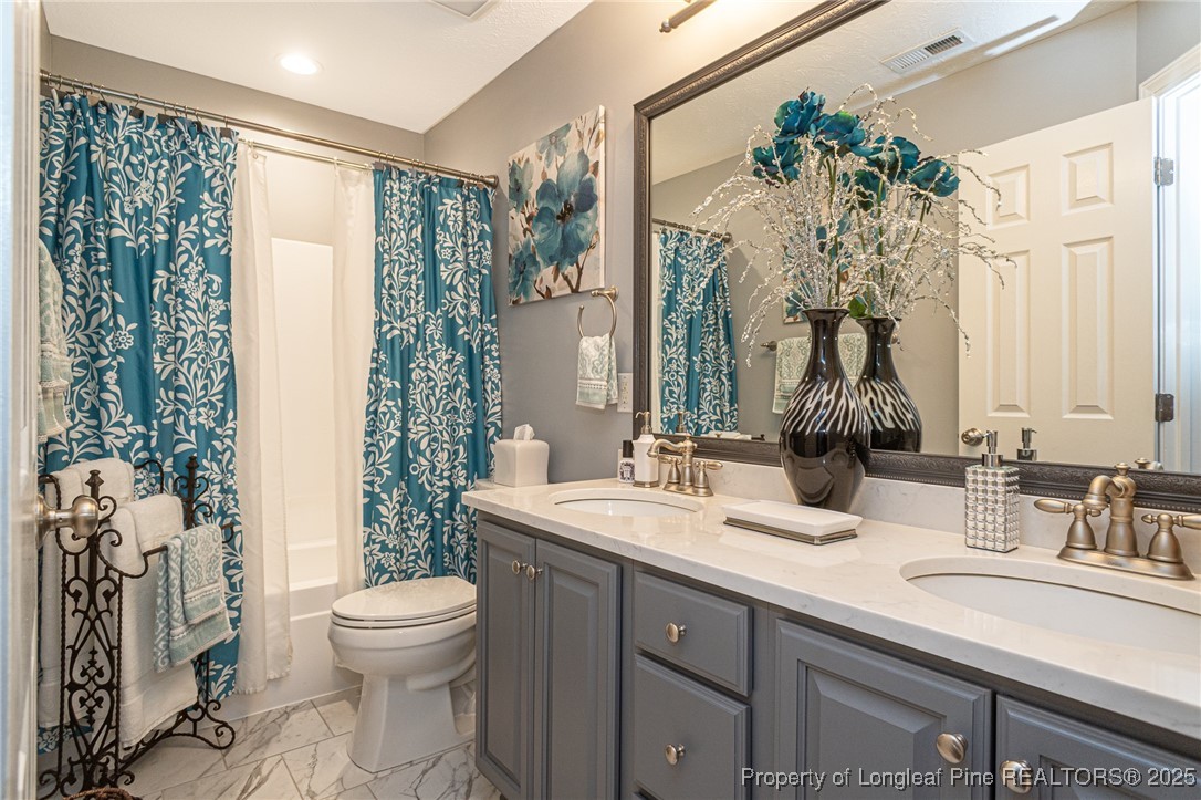 595 Whispering Pines Drive Spring Lake, NC 28390 - Photo 31 of 48 a bathroom with a sink a toilet and a mirror