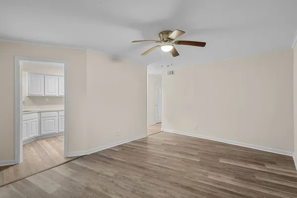 an empty room with wooden floor fan and windows