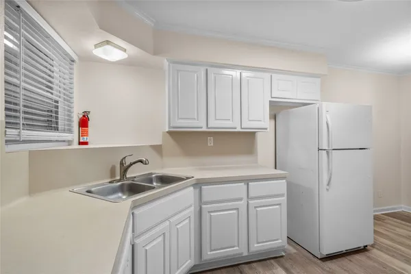 a kitchen with white cabinets sink and refrigerator