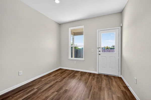 a view of an empty room with wooden floor and a window