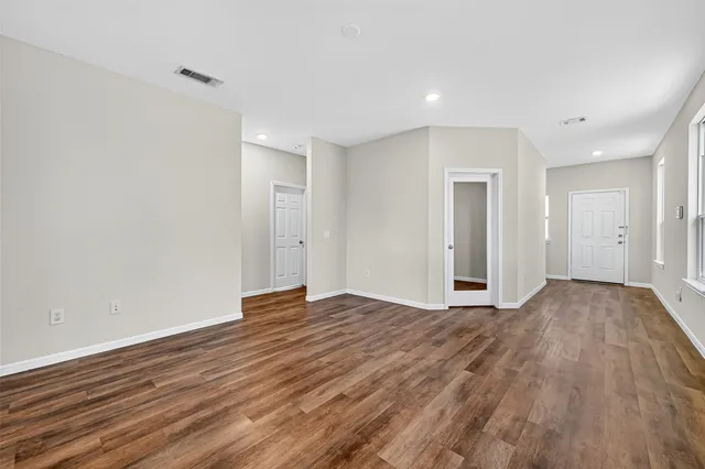 a view of an empty room with wooden floor and closet