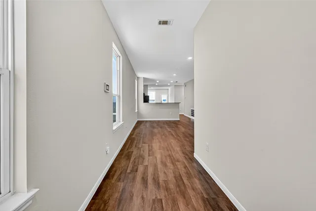 a view of a hallway with wooden floor and a bathroom