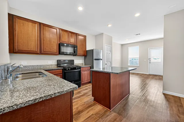 a kitchen with stainless steel appliances granite countertop wooden cabinets a stove top oven a sink and dishwasher