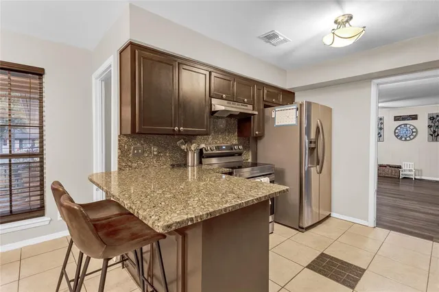 a kitchen with stainless steel appliances granite countertop a sink refrigerator and cabinets